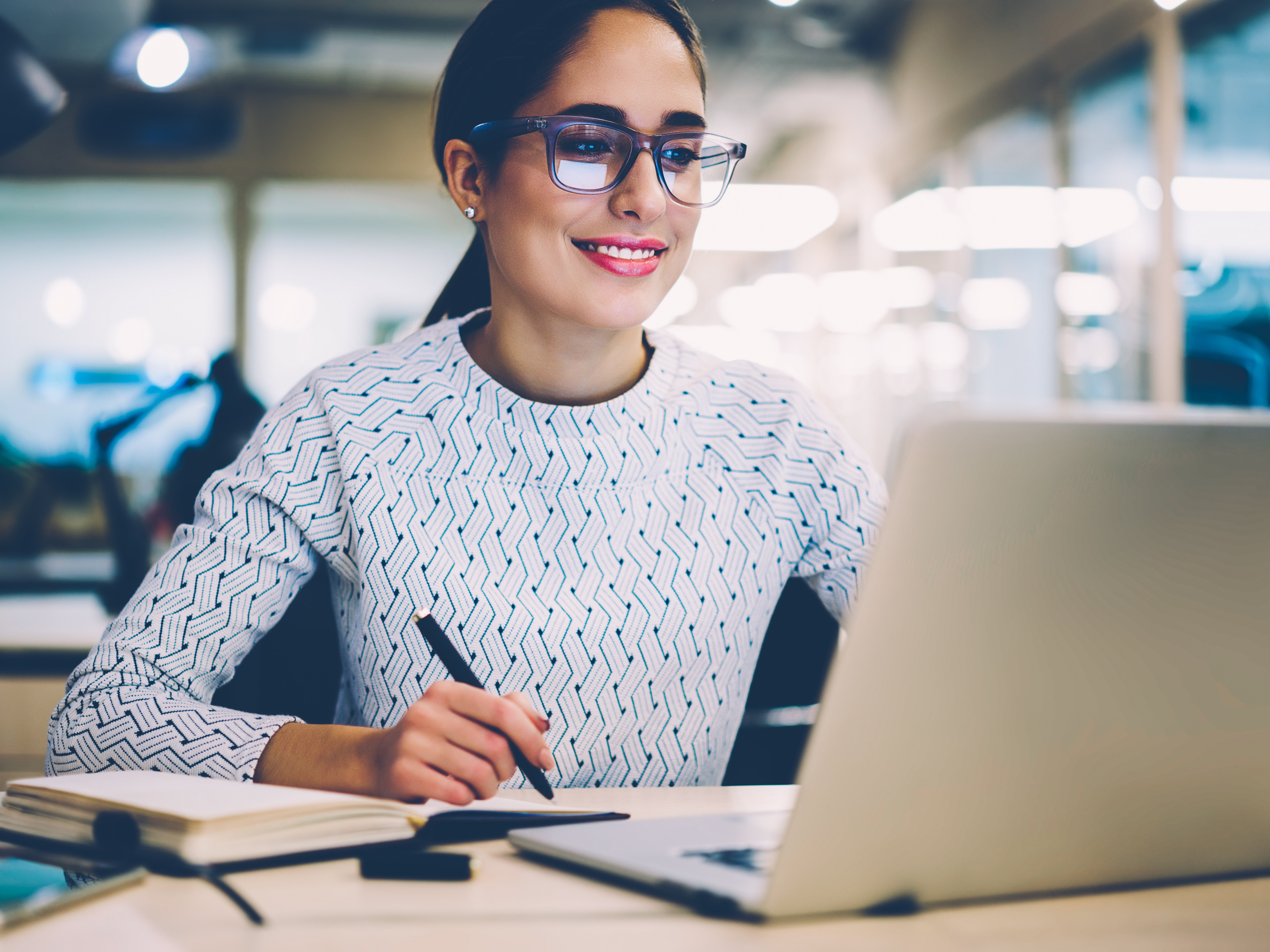 Eine Person sitzt an einem Laptop und lächelt.