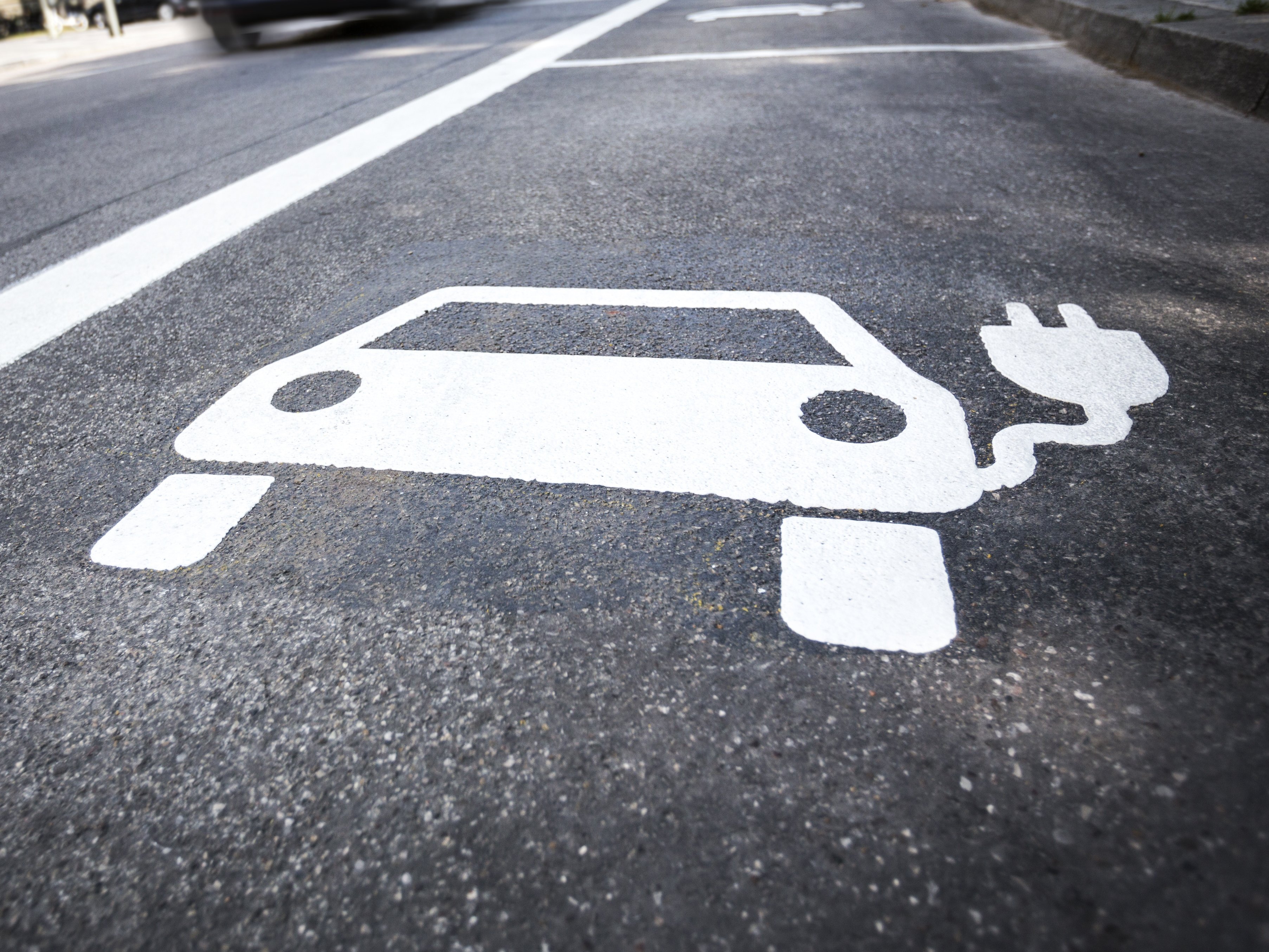 Ein Piktogramm eines Elektrofahrzeuges auf einer Straße.