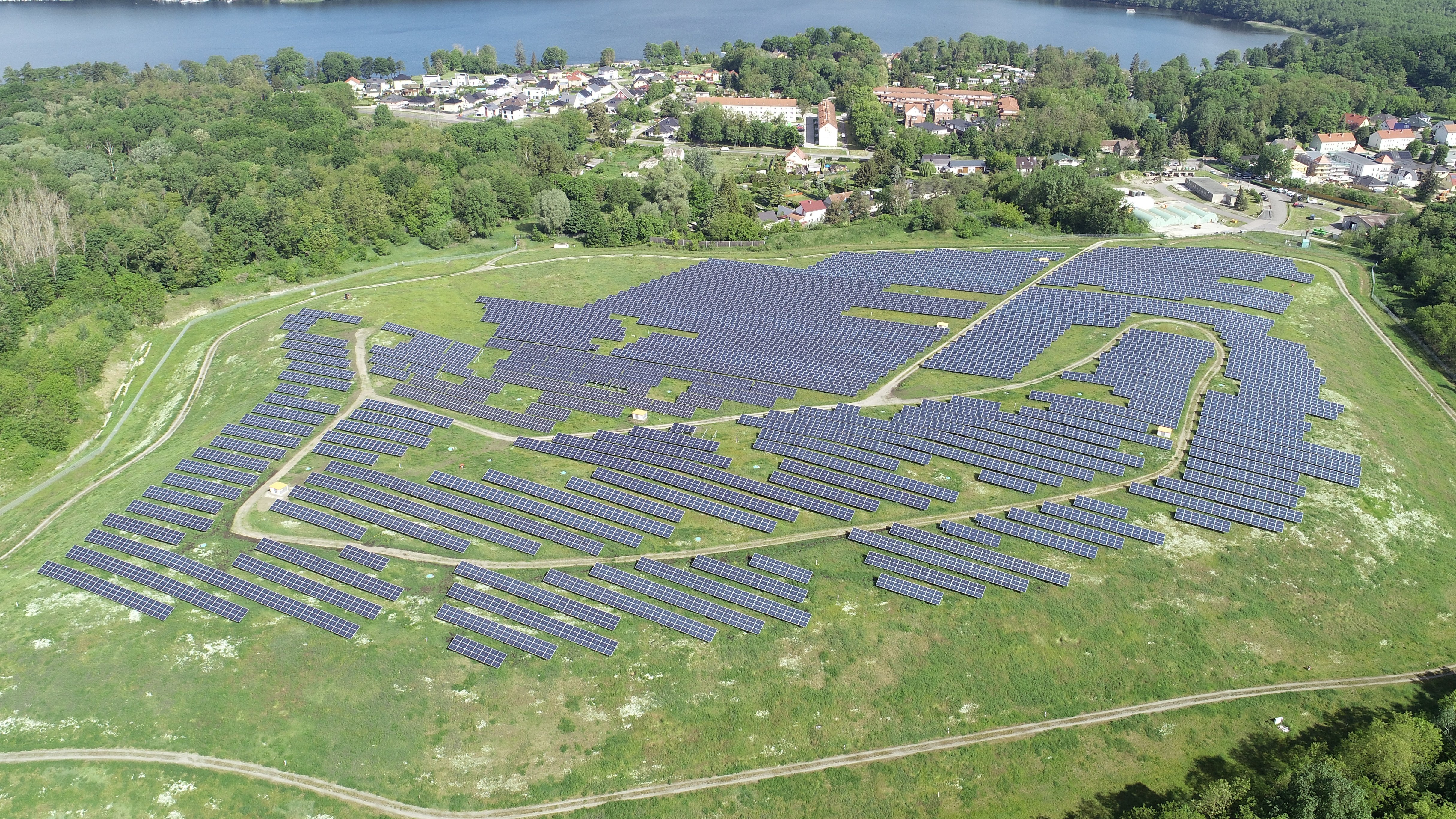 Weite Photovoltaik‑Freiflächenanlage: Zahlreiche dunkelblau‑schwarze Solarpanels reihen sich parallel auf einem offenem Feld.